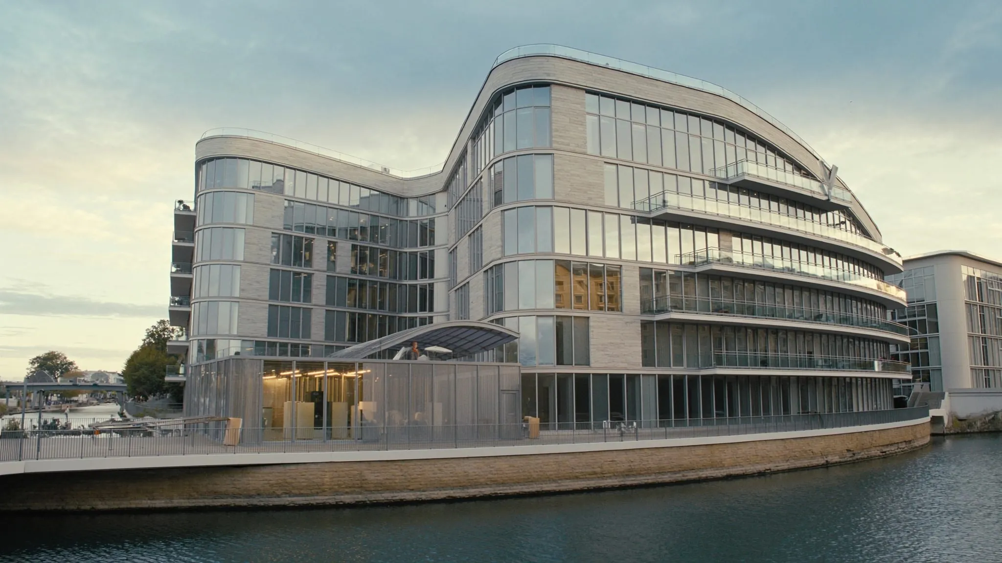 Architecture contemporaine de verre et d'acier au bord de l'eau, ciel clair de fin de journée