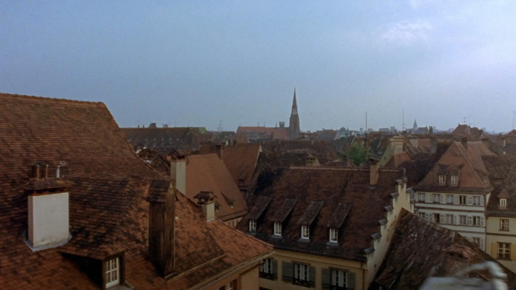 Toits d'ardoise de Strasbourg et flèche de la cathédrale émergeant dans une lumière douce
